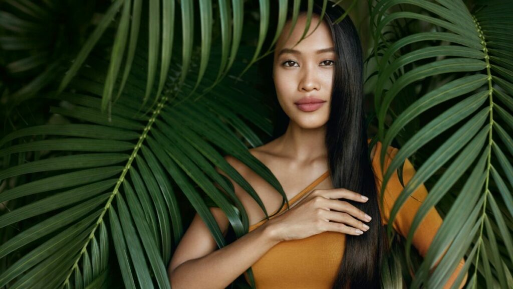 Asian-girl-with-long-hair-nestled-between-palm-leaves